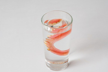 denture in a glass with water on a white background