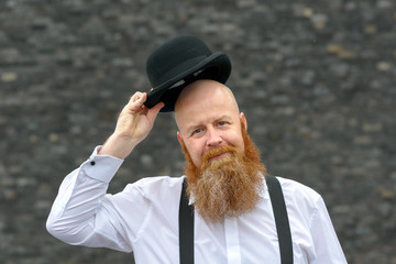 Polite bald bearded man doffing his hat