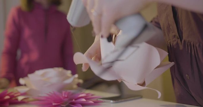 applying glue with a hot glue gun on paper pedals to create paper flowers (slow motion).