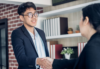 young asian businessman and businesswoman handshake about business agreement at meeting table in modern office.business partnership concept.satisfied the deal with client negotiation.