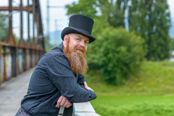 Fototapeta premium Smiling friendly bearded man leaning on a bridge