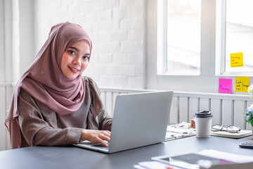 Happy beautiful muslim business woman brown hijab working about financial with business report and calculator in home office.