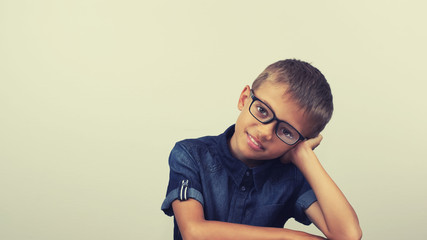 Banner Schoolboy in a blue shirt sitting at the table. Boy with glasses on white background Concept back to school