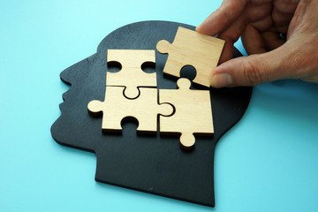 Problem solving concept. Hand puts piece of puzzle on head shape.