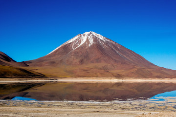 Blue sky, alpine lake and the snow-capped volcano in the Bolivian Andes