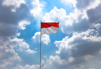 Red and White, Indonesia National Flag High on The Sky Blowing by Wind on 17 August During Independence Day Celebration Against Cloudy Blue Sky.