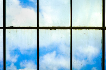 Cloud Behind A Very Dirty Dim Windows Full of Dust Dirt and Mildew That Need To Be Clean at The Top of High Rise Building or Skysrapper. From Inside Looking Outside or Unclear Vision Concept
