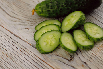 Slices of fresh green cucumber on a gray wooden background. Side view, horizontal, close-up, free space, cropped shot. Healthy eating concept.