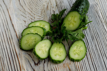 Slices of fresh green cucumber on a gray wooden background. Side view, horizontal, close-up, free space, cropped shot. Healthy eating concept.