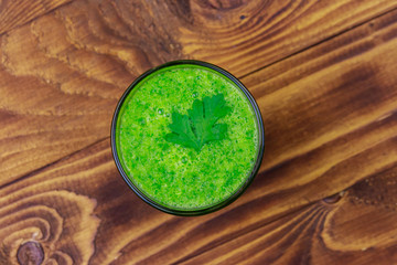 Fototapeta na wymiar Glass of green detox smoothie of cucumber and parsley on a wooden table. Top view