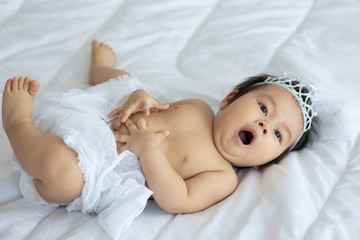 Cute Sweet Adorable Asian Baby wearing bride dress and diadem Sitting on white bed smiling and playing with happiness emotional in cozy bedroom,Healthy Baby Concept