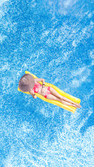 Beautiful young woman in hat in swimming pool aerial top view from above, young girl in bikini relaxes and swims on inflatable mattress and has fun in water on family vacation, tropical holiday resort