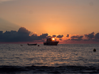 Fototapeta na wymiar Sunrise and boat in mediterranean sea. Pantelleria Island, Italy