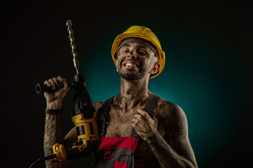 A man miner in a worker s clothes and a helmet, dirty, in soot, with a naked body, grimaces at the...