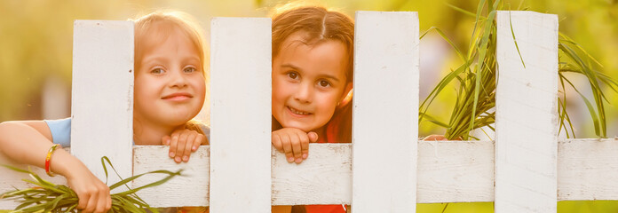 Two beautiful young girls in the garden fence
