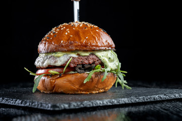 Burger with olives, tomatoes, herbs and pesto.