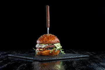 Burger with olives, tomatoes, herbs and pesto.