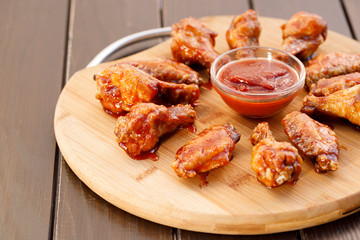 Spicy deep fried chicken wings and legs with dipping sauce on wooden plate , wood background.