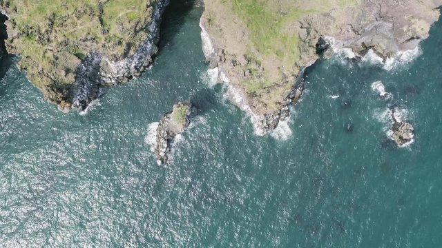 Majestic 4K bird's-eye view aerial of the turquoise North Atlantic ocean and seagulls flying by the cliffs of Hellnar and Arnarstapi, both popular tourist attractions on the west coast of Iceland.