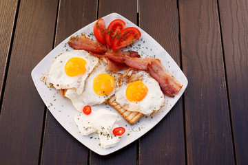 Healthy bacon fried egg on toast bread breakfast on plate , fresh tomatoes and cheese on plate , wood background.