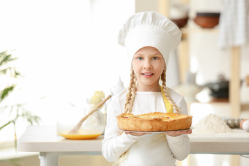 Cute little chef with pie in kitchen