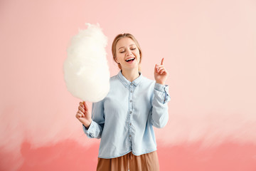 Beautiful woman with cotton candy on color background