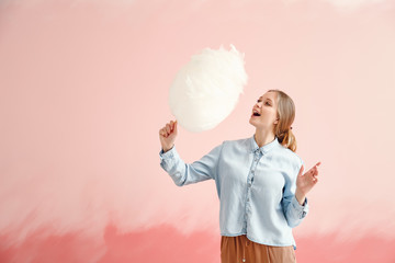 Beautiful woman with cotton candy on color background