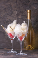 Tasty cotton candy with sweets in glasses on grey background