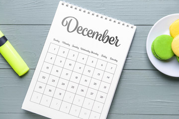 Flip paper calendar and cakes on wooden background