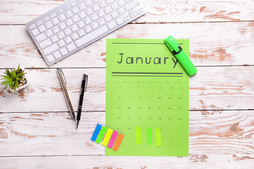 Paper calendar, PC keyboard and stationery on light wooden background