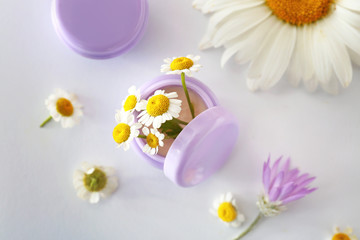 Fototapeta na wymiar Jar of cream with chamomile flowers on white background