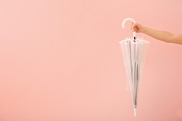 Female hand with stylish umbrella on color background
