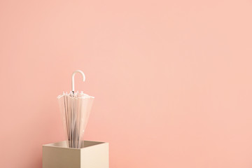 Stylish umbrella with box on color background