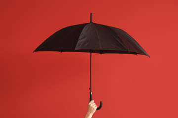 Female hand with stylish umbrella on color background