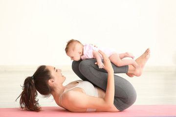 Mother practicing yoga with cute little baby at home