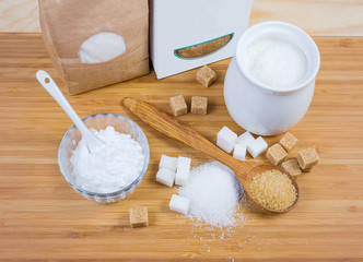 White and brown sugar in different forms on wooden surface