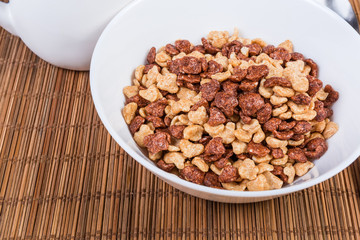 Breakfast cereal in bowl on the bamboo table mat close-up