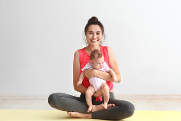 Mother practicing yoga with cute little baby indoors