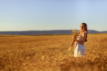 Beautiful young woman in wheat field at sunset outdoor .