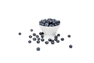Fototapeta na wymiar Blueberry berry in a white bowl and scattered around on a white background isolated