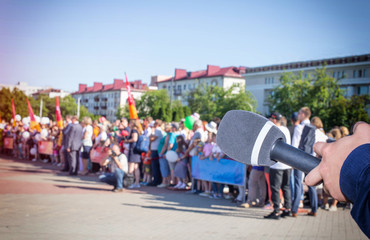 Obraz premium The microphone on the background of a crowd of people in the square concept of freedom of speech and interview. Rally on the square, strike, copy space, public opinion