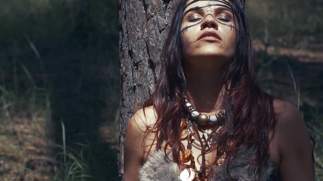 Young brunette amazon woman is resting under the tree in the forest