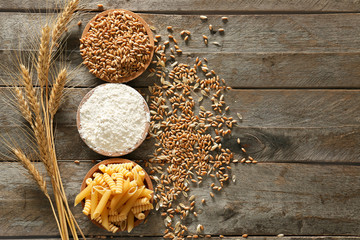 Raw pasta with wheat flour and grains on wooden table