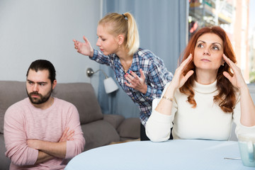 Husband and wife quarrelling indoors, senior mother taking it hard