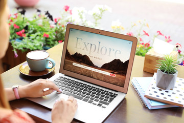 Woman with laptop visiting travel agency website while sitting in cafe