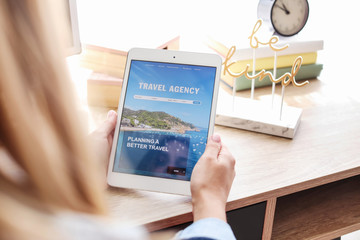 Woman with tablet computer visiting travel agency website at home