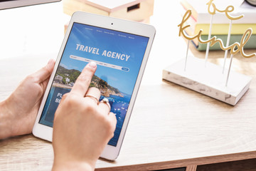Woman with tablet computer visiting travel agency website at home