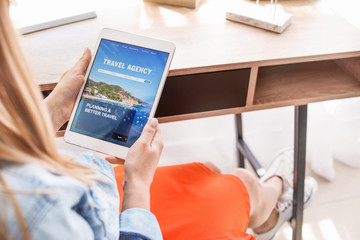 Woman with tablet computer visiting travel agency website at home