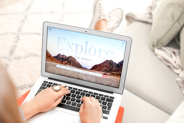 Woman with laptop visiting travel agency website at home