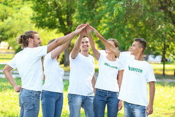 Team of volunteers putting hands together outdoors